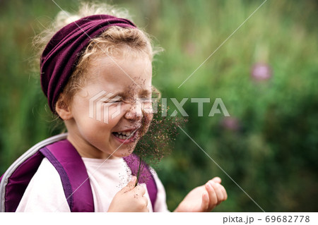 Portrait of small toddler girl outdoors in summer nature, tickling face with grass. Portrait of small toddler girl outdoors in summer nature, tickling face with grass. 69682778