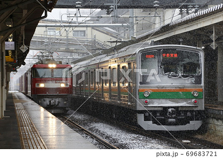 雪の日の黒磯駅に留置中の宇都宮線5系と貨物列車の写真素材