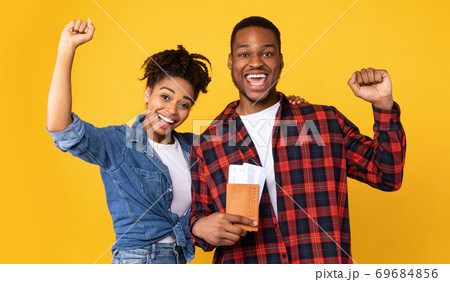 Joyful African American Couple Holding Flight Tickets On Yellow Background Joyful African American Couple Holding Flight Tickets On Yellow Background 69684856