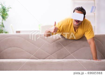 Young man with virtual reality glasses at home 69685988