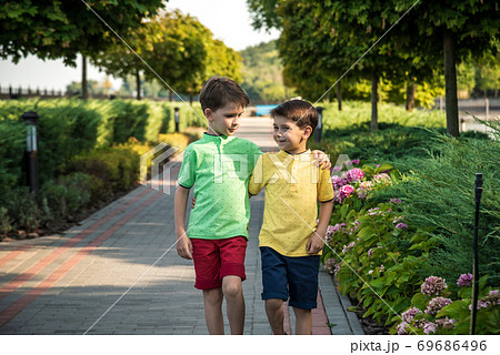 childhood, hiking, family, friendship and people concept - two happy kids walking along forest path childhood, hiking, family, friendship and people concept - two happy kids walking along forest path 69686496
