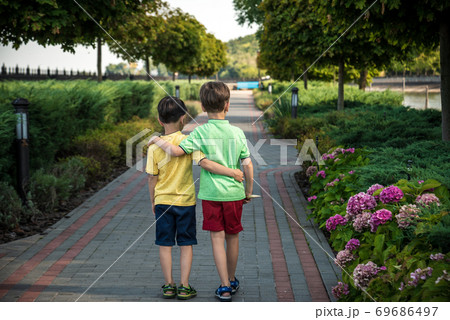 childhood, hiking, family, friendship and people concept - two happy kids walking along forest path 69686497