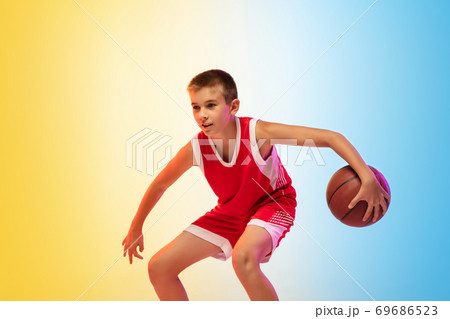Full length portrait of a young basketball player with ball on gradient background 69686523