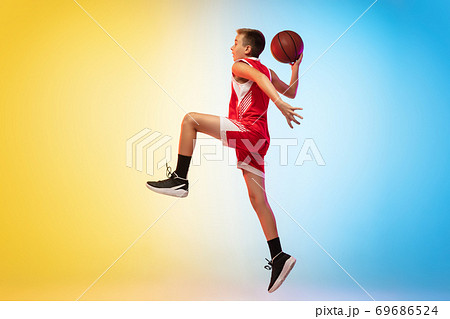 Full length portrait of a young basketball player with ball on gradient background 69686524