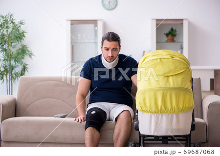 Young man after accident looking after newborn 69687068