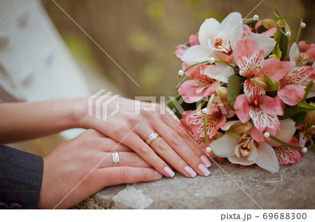 Male and female hands with wedding rings and bouquet 69688300