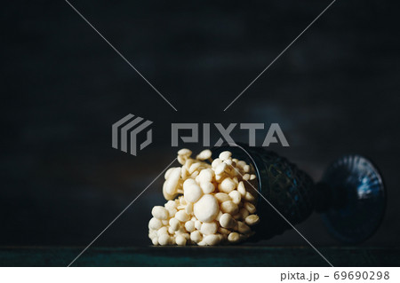 Still life with little white mushrooms putted in blue wine glass on dark 69690298