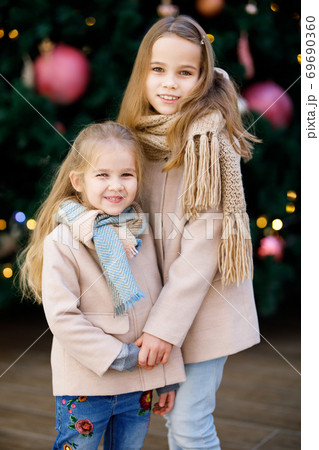 little girls in coats near large Christmas tree 69690360