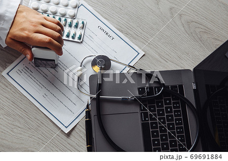 Male doctor in public medical office is stamping medical document. Healthcare concept. Top view 69691884