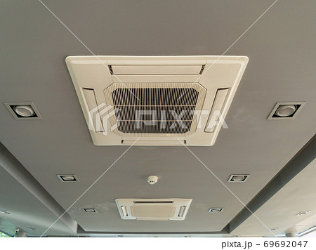 Modern white ceiling mounted cassette type air conditioner in office building system work. Ventilation compressor. Modern white ceiling mounted cassette type air conditioner in office building system work. Ventilation compressor. 69692047