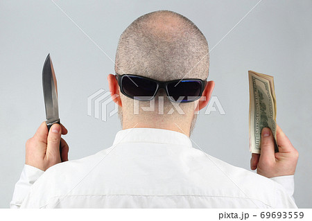 man stands with his back with money and a knife in his hands. man stands with his back with money and a knife in his hands. 69693559