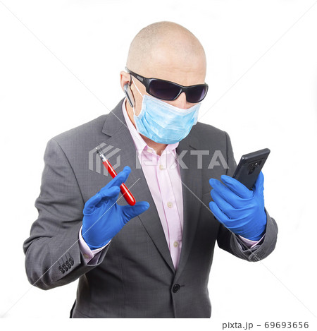 Successful businessman in a protective mask and gloves works on a smartphone during quarantine  69693656