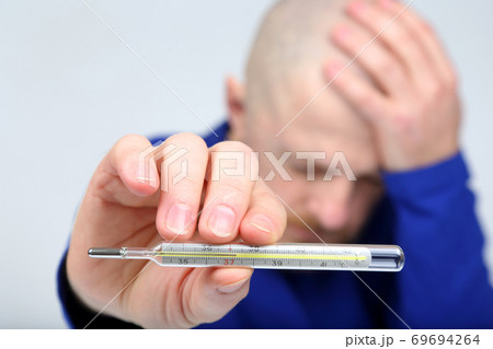 man shows a thermometer with a high temperature man shows a thermometer with a high temperature 69694264