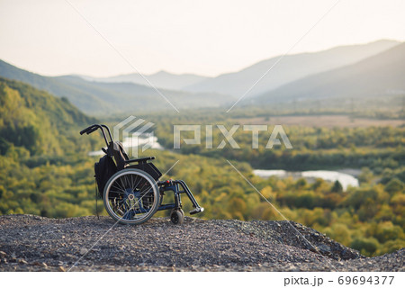 Empty wheelchair on the mountains at sunset. Concept of travel of people with disabilities. 69694377
