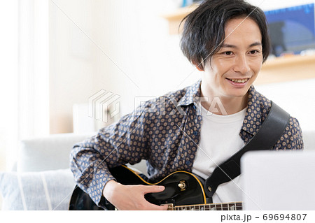 オンラインでバンド演奏をする男性【リビング】 オンラインでバンド演奏をする男性【リビング】 69694807