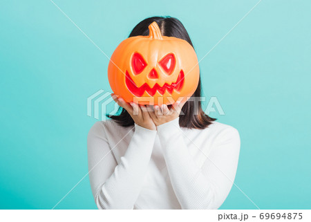woman holding orange model pumpkins at her head 69694875