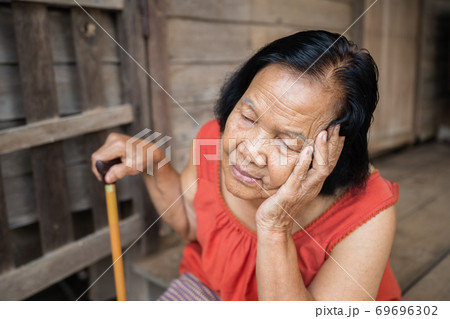 Thai elderly woman in round-necked sleeveless collar with headache and worried stressed face in home 69696302
