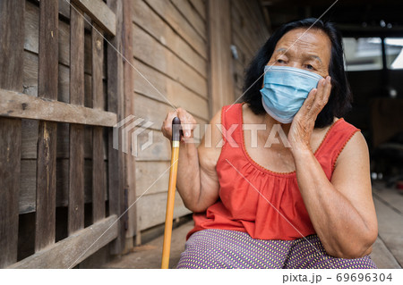 Thai elderly woman in round-necked sleeveless collar wearing medical mask for protect coronavirus  69696304