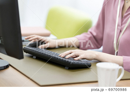 デスクトップパソコンのキーボードを打つ女性の手元の写真素材