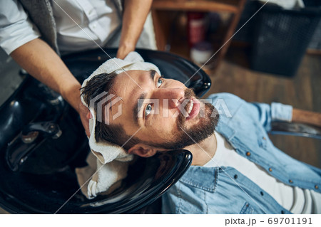 Bearded brunette man getting a barbershop staff dry his hair 69701191