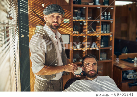 Fancy barber getting ready to shave his client beard 69701241
