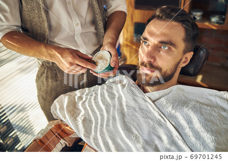 Professional hairdresser holding shaving cream and a brush 69701245