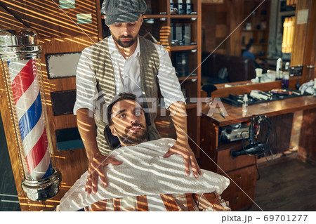 Responsible hair-grooming specialist providing his visitor with a towel 69701277