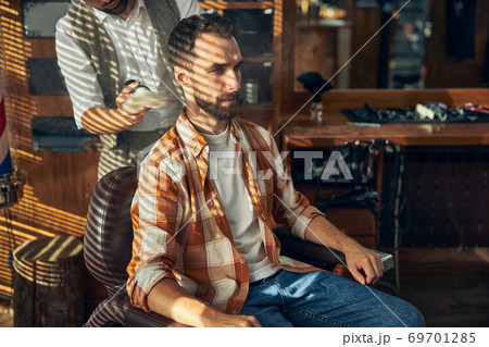 Brunette young man getting a fresh shave a barbershop 69701285