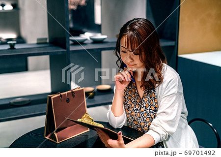 店内のテーブルに座ってアンケートに答える若い女性 69701492