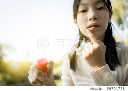 Asian child girl maintains her lips,skin care and protection, chapped lips,dry mouth that have lost moisture,beautiful female teenage applied balm to repair her lips in winter cold,woman with natural Asian child girl maintains her lips,skin care and protection, chapped lips,dry mouth that have lost moisture,beautiful female teenage applied balm to repair her lips in winter cold,woman with natural 69701728