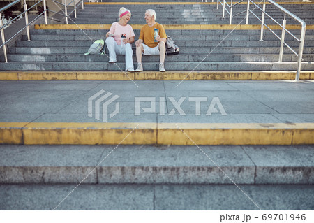Pleased modern pensioners sitting on the stairs Pleased modern pensioners sitting on the stairs 69701946