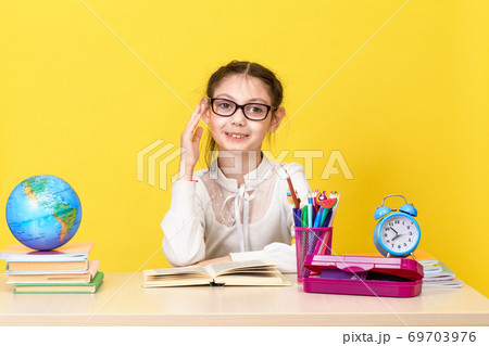 The schoolgirl sits at the desk and raises her hand for an answer. Back to school. The new school year. 69703976