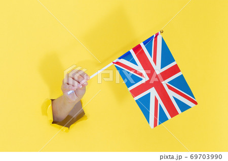 Hand holding English flag from yellow torn paper. United Kingdom flag 69703990