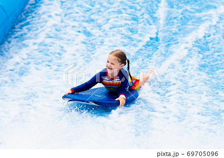 Little girl surfing in beach wave simulator 69705096