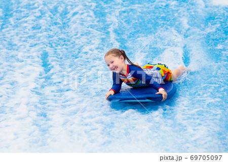 Little girl surfing in beach wave simulator Little girl surfing in beach wave simulator 69705097