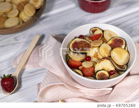 Trendy home breakfast with small pancakes and strawberry, currant and slieces of figs on white table. Top view of treandy breakfast. Trendy home breakfast with small pancakes and strawberry, currant and slieces of figs on white table. Top view of treandy breakfast. 69705260