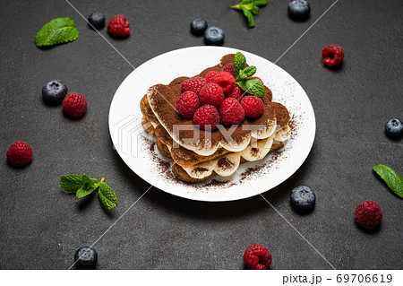 portion of Classic tiramisu dessert with raspberries and blueberries on dark concrete background portion of Classic tiramisu dessert with raspberries and blueberries on dark concrete background 69706619