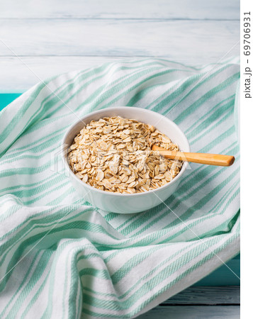 Oatmeal flakes in bowl on green napkin 69706931