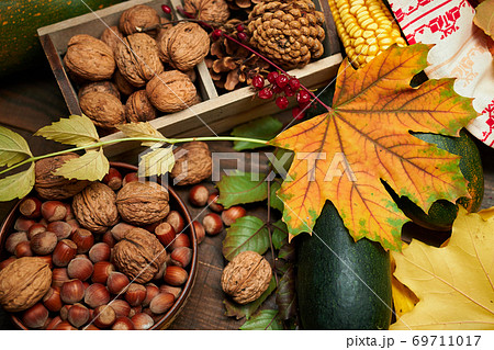 autumn still life in rustic style as a background - leaves, vegetables and fruits, nuts and other natural food ingredients on wooden boards 69711017