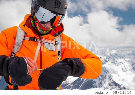Close-up Portrait of a stern climber skier in sunglasses and a cap with a ski mask on his face. against the backdrop of Mount Elbrus 69711514