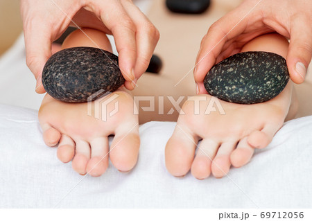 Masseur making foot massage with stones. 69712056