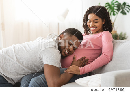 Happy black man listening to his pregnant wife belly 69713864