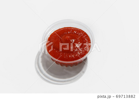 Red ketchup for fast food in menu for delivery during quarantine. Yummy tomato ketchup in plastic container with shadow 69713882