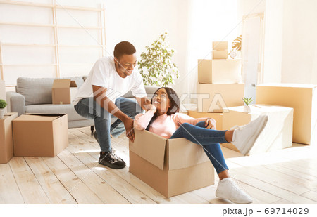 Black woman and her boyfriend playing together with cardboard box during relocation 69714029