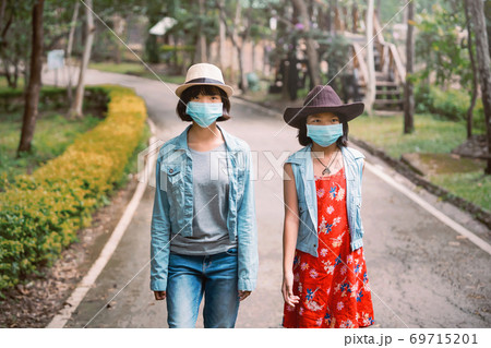 two asian woman travel wearing face protection in prevention for coronavirus during wlaking in park 69715201