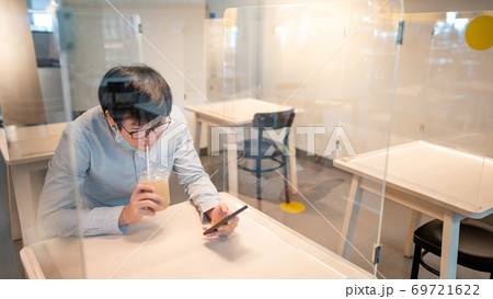Drinking coffee in shield partition for social distancing 69721622