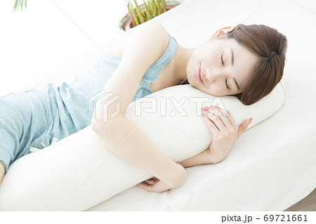 抱き枕を抱いて眠る女性 69721661