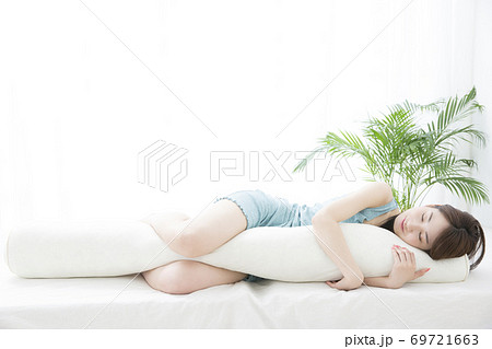 抱き枕を抱いて眠る女性 69721663