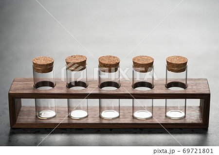 walnut holder with glass tubes for spices on concrete surface walnut holder with glass tubes for spices on concrete surface 69721801
