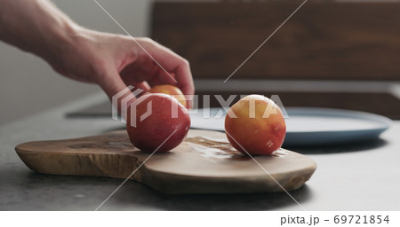 man put nectarines on a olive wood board man put nectarines on a olive wood board 69721854